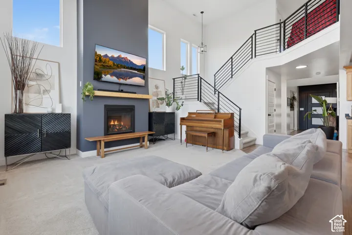 Two-story ceilings with high windows, an integrated fireplace, a wooden mantel, and a modern stair railing