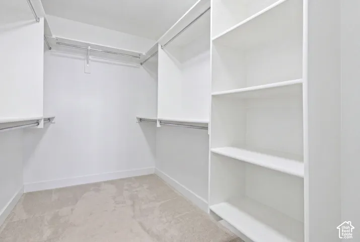 Spacious walk-in closet featuring multiple built-in shelving units, dual hanging rods at varying heights, and neutral finishes throughout