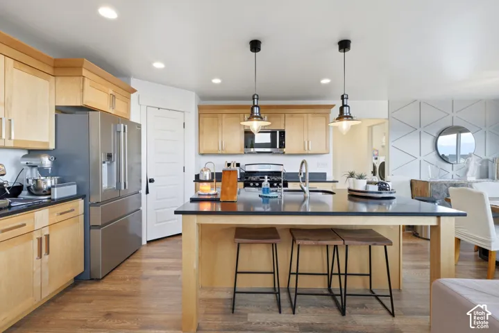 Kitchen featuring stainless steel appliances, wood-finish cabinetry, a large island with a dark countertop, and recessed lighting