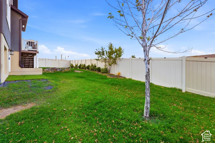 Expansive backyard featuring a manicured lawn, established tree, and a full privacy fence