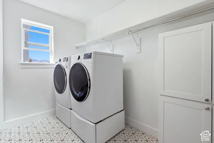 White cabinetry with silver hardware, patterned floor tiling, and a window providing natural light