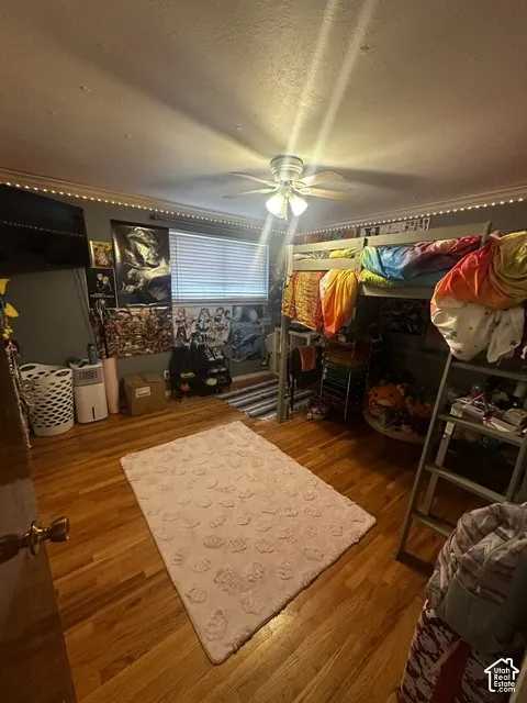 Hardwood flooring, ceiling fan with integrated lighting, window with blinds, crown molding, and built-in bunk bed