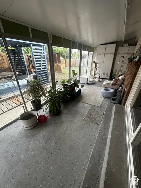 Enclosed patio space with full glass paneling, concrete flooring, and a brick-finish accent wall