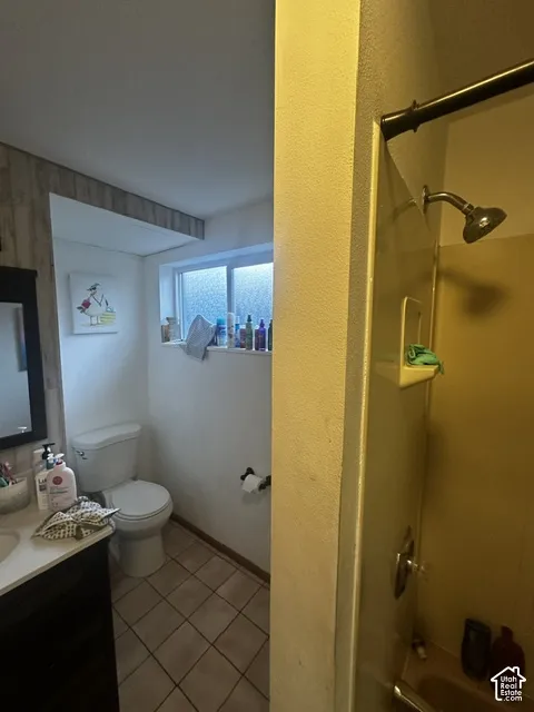 Bathroom featuring a vanity with a white countertop, a white toilet, tiled flooring, and a shower with a dark bronze shower rod and showerhead