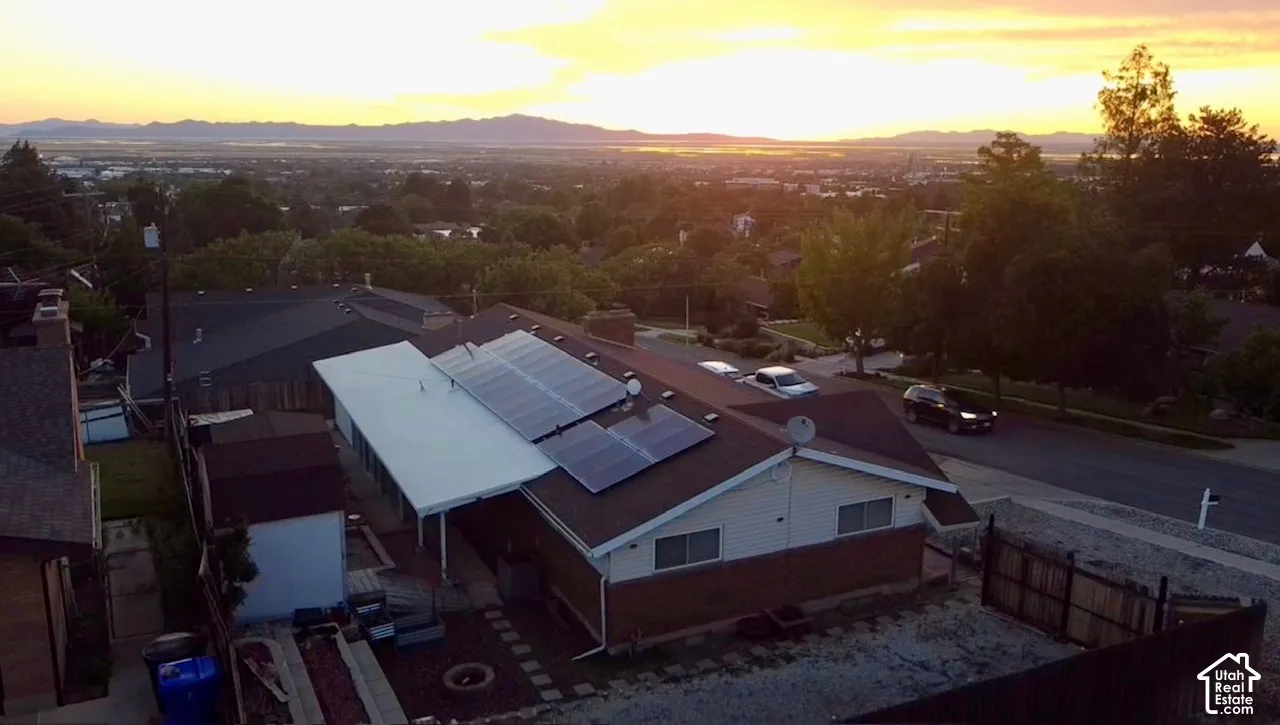 Solar panel array, sloped brown shingle roof, beige siding exterior, covered patio, fenced yard