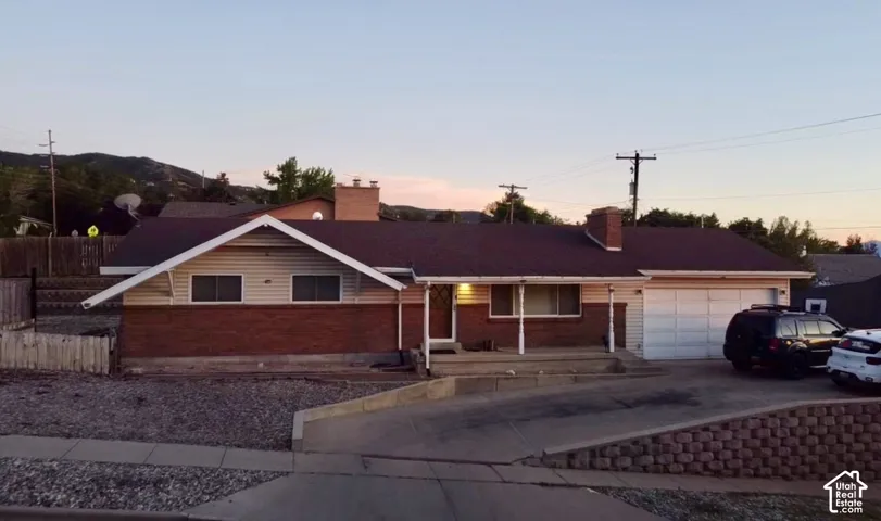 Exterior featuring brick and siding facade, attached garage, covered entryway, and a sloped driveway