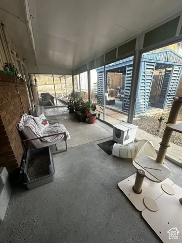 Enclosed sunroom with a brick-finish wall, screened windows, and concrete flooring