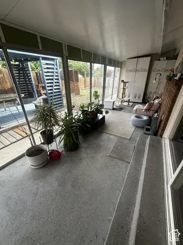 Enclosed patio space with full glass paneling, concrete flooring, and a brick-finish accent wall