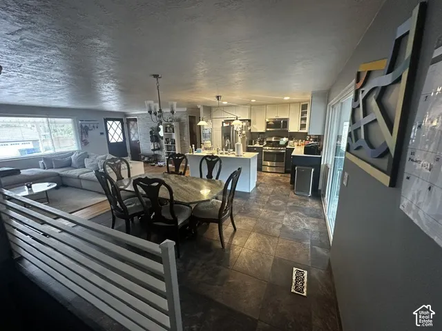 Spacious dining area featuring a chandelier, tile flooring, and a sliding glass door