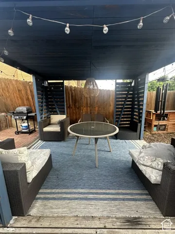Covered outdoor patio featuring a slatted privacy wall, string lighting, and a hanging light fixture
