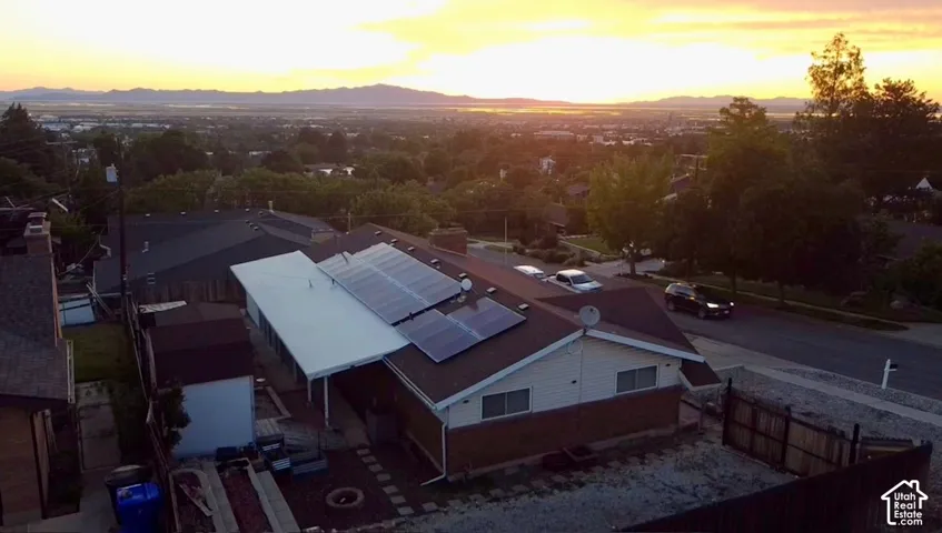 Solar panel array, sloped brown shingle roof, beige siding exterior, covered patio, fenced yard