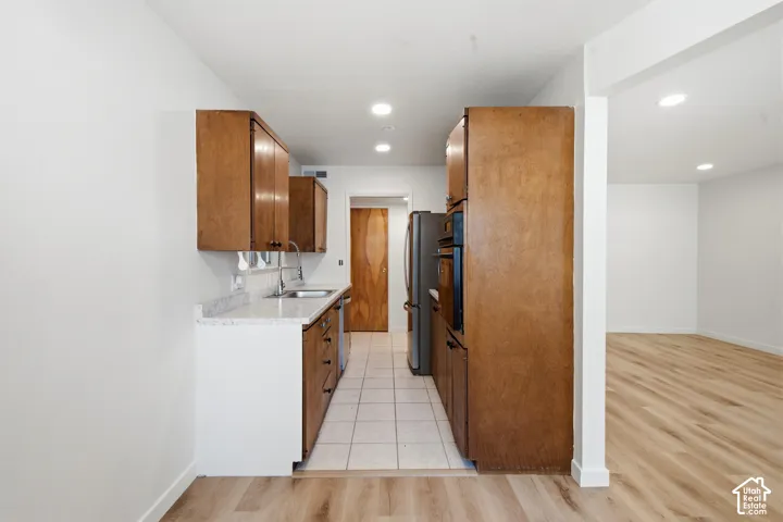 Galley kitchen with wood-finish cabinetry, light-toned countertops, and tile flooring