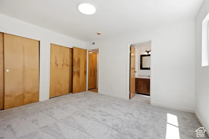 Plush carpet flooring, recessed ceiling light, wood-finish bi-fold closet doors, and painted white walls