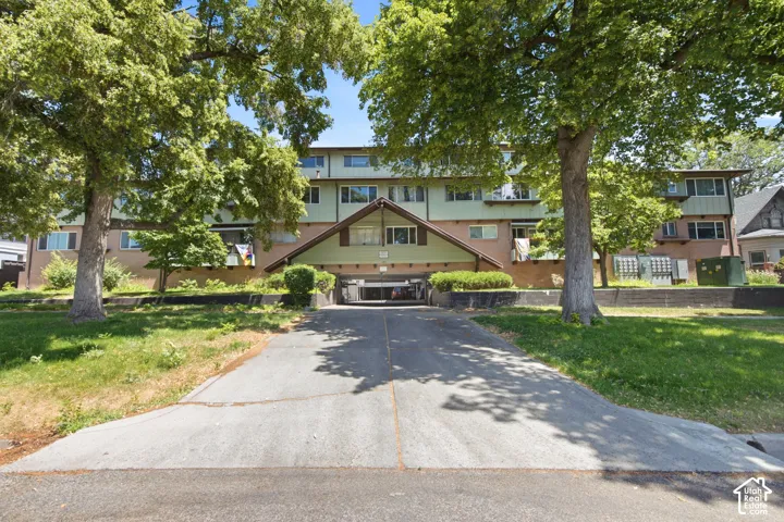 Multi-story building exterior with a pitched roof entryway, an integrated garage, and a paved driveway