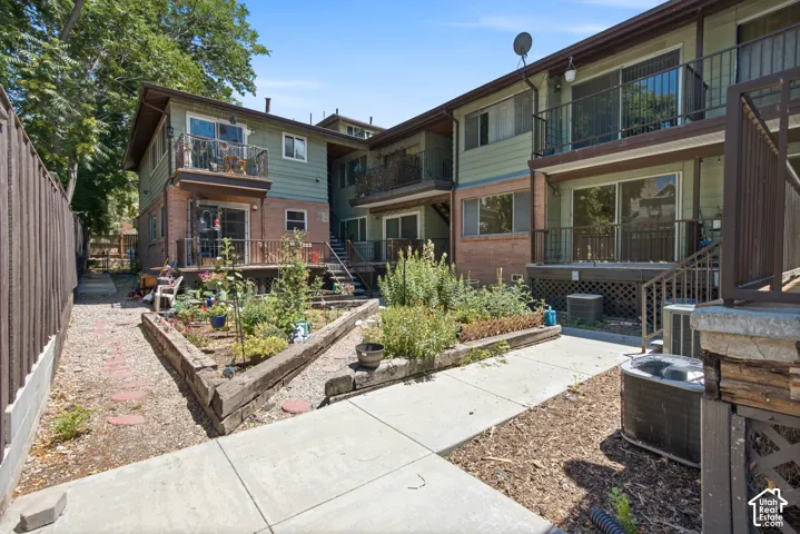 Multi-level building with individual balconies, exterior stairs, and a raised garden bed