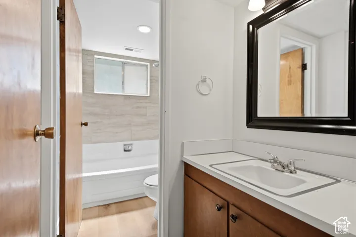 Vanity with white countertop, integrated sink, and wood-finish cabinetry