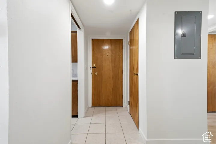 Tiled flooring entryway featuring a wood-finish door, overhead lighting, and white walls