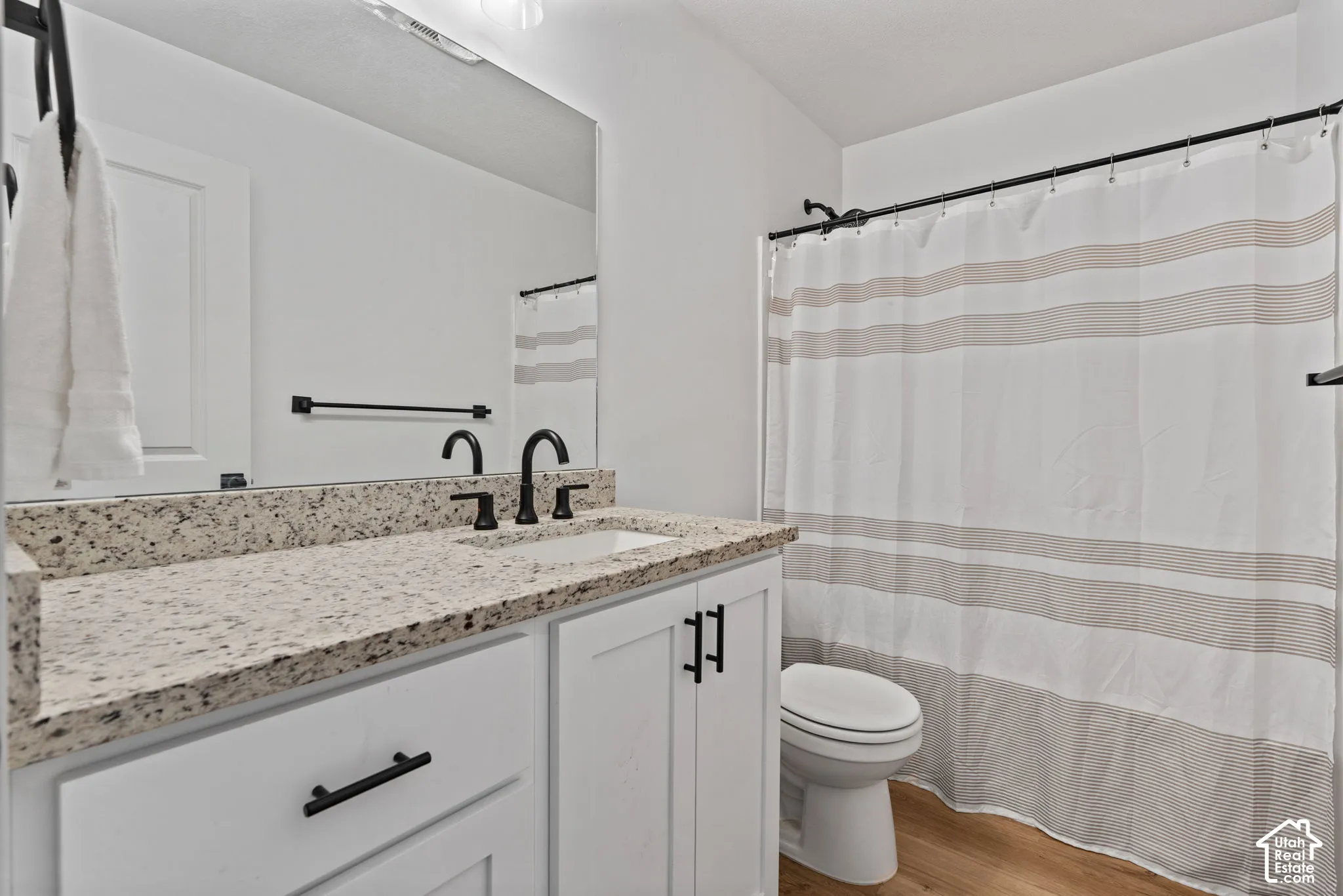 White vanity with dark hardware, speckled countertop, and a rectangular sink