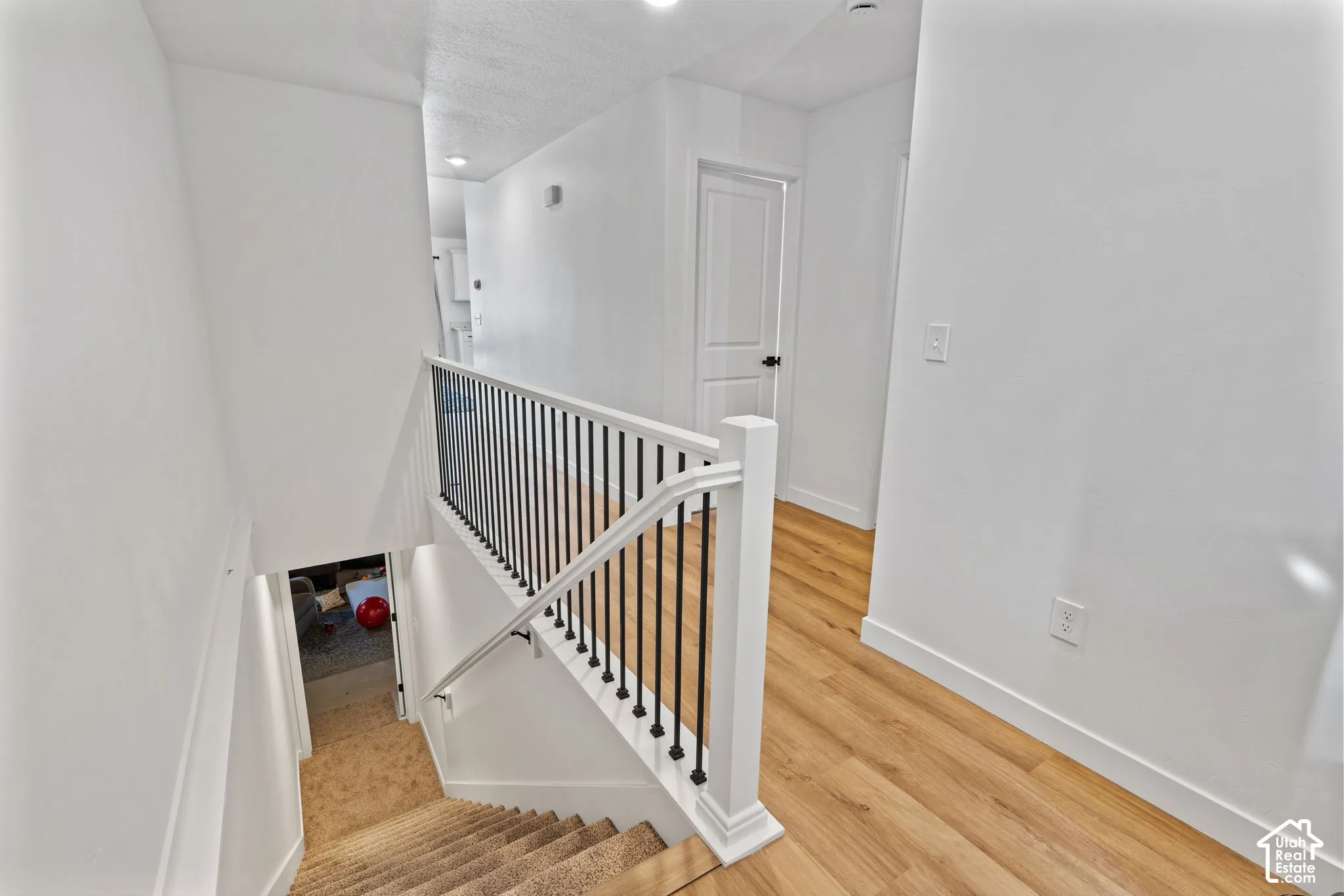 Hallway featuring wood-finish flooring, white walls, and recessed lighting