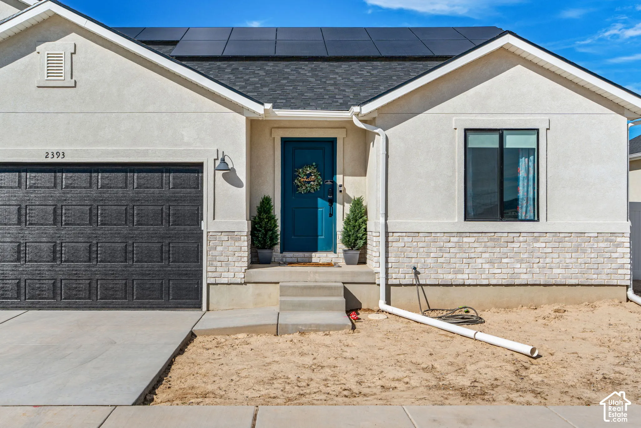 Stucco exterior with a dark blue entry door, stone veneer accents, and a dark asphalt shingle roof