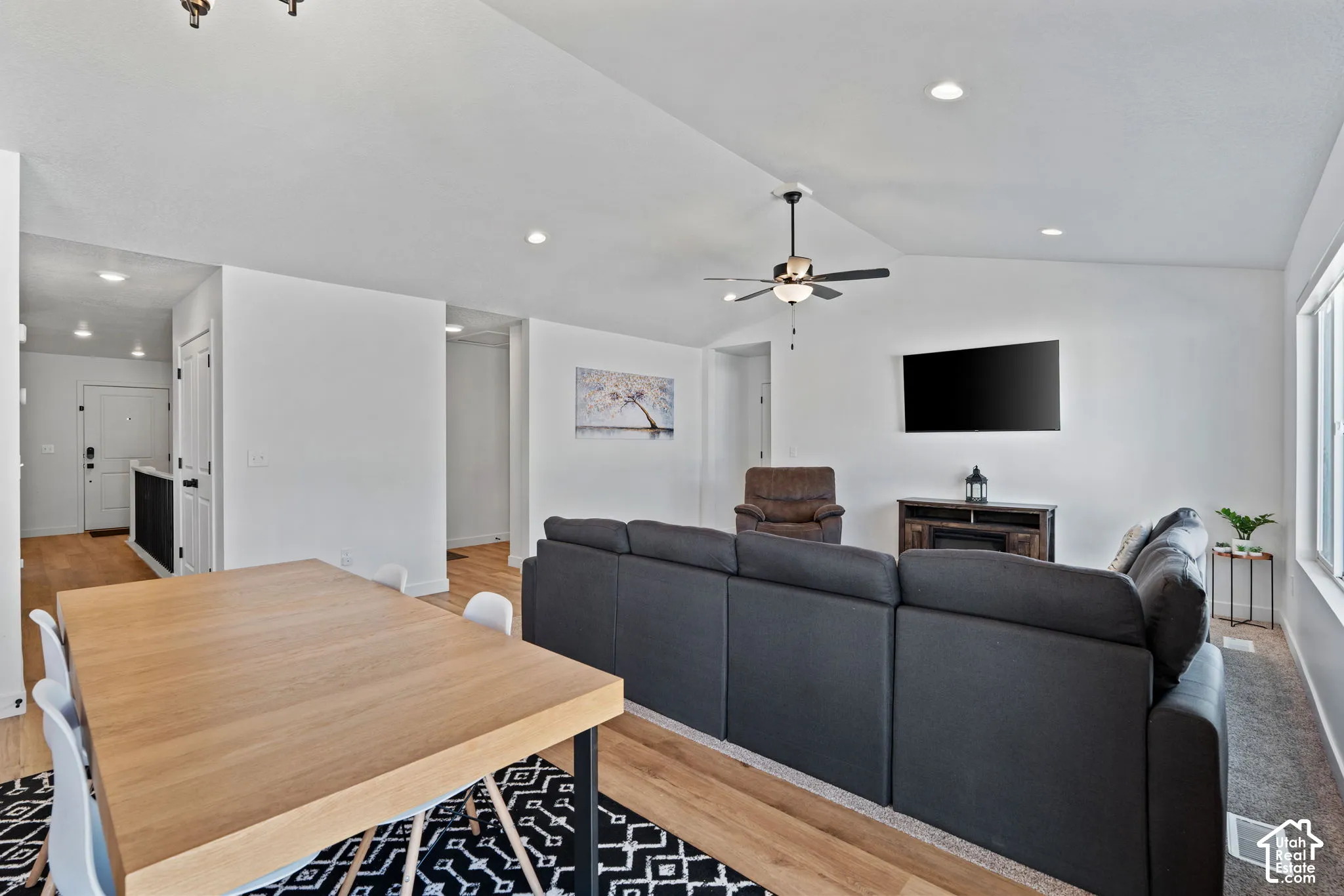 Vaulted ceiling with a ceiling fan, recessed lighting, wood-finish flooring, and light-toned wall finishes