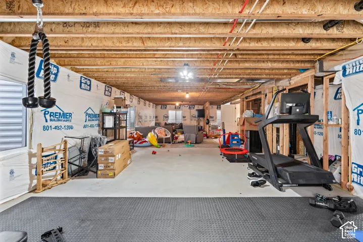 Unfinished basement with exposed ceiling joists, framed wall sections, concrete flooring, and an egress window