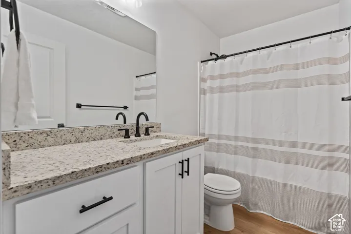 White vanity with dark hardware, speckled countertop, and a rectangular sink