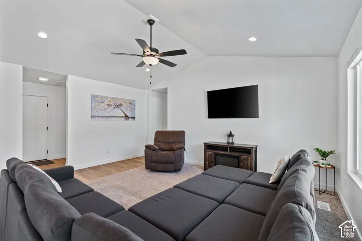Vaulted ceiling with a ceiling fan, recessed lighting, wood-finish flooring, and a built-in media console with an electric fireplace