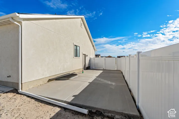 Exterior stucco finish, concrete patio, white vinyl fencing, and a side access door