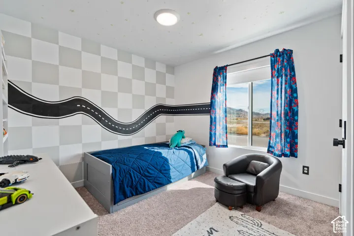 Carpeted flooring, white walls, built-in shelving, and a prominent window