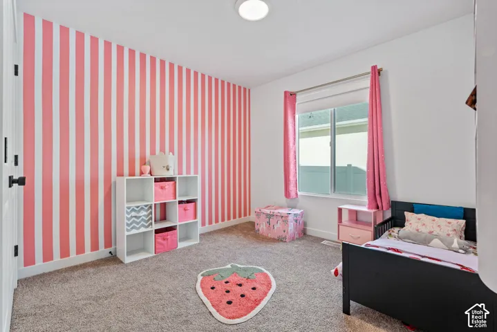White walls with a bold striped accent wall, light-colored carpeting, a window with a roller shade, and a flush-mount ceiling light fixture