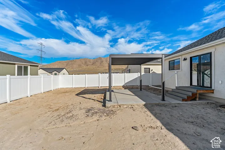 Sliding glass doors, concrete patio, modern pergola, composite decking, and white vinyl fencing