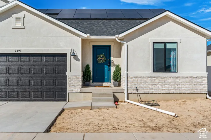 Stucco exterior with a dark blue entry door, stone veneer accents, and a dark asphalt shingle roof
