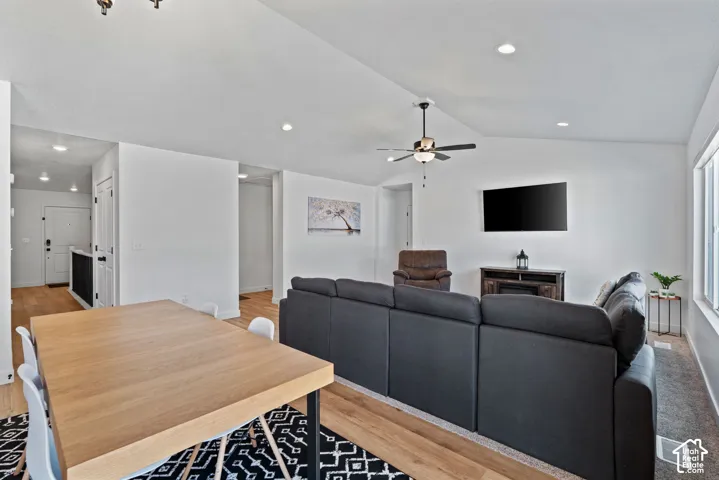 Vaulted ceiling with a ceiling fan, recessed lighting, wood-finish flooring, and light-toned wall finishes