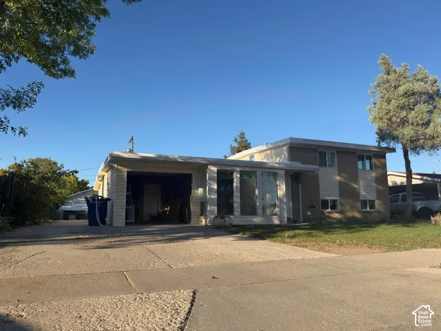 Split-level property featuring a covered carport, attached garage, and a concrete driveway