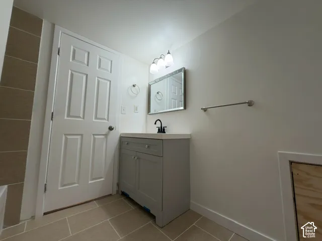 Gray vanity with a light-colored countertop, wall-mounted mirror, and tile flooring
