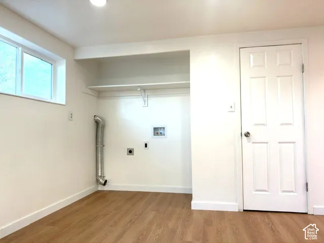 Laundry area featuring wood-finish flooring, a double-panel interior door, and a built-in shelf