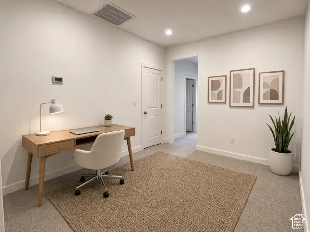 Recessed lighting illuminates neutral-toned walls and plush carpeting, complemented by white trim and a solid core door