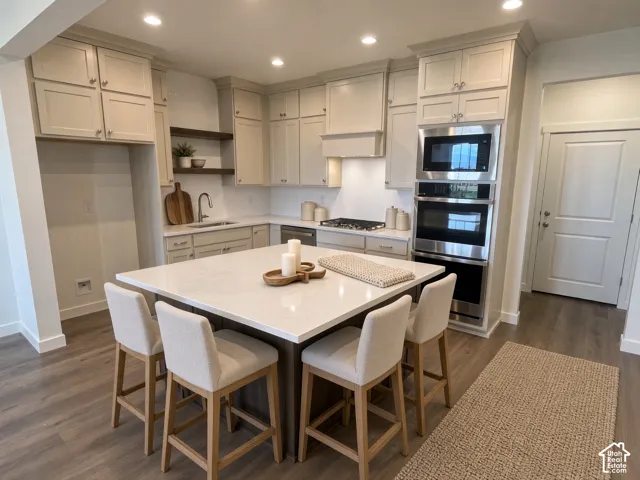 Kitchen featuring a central island with countertop, shaker-style cabinetry, stainless steel appliances, and wood-finish flooring