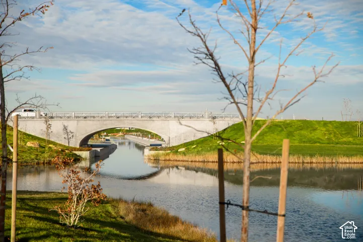 Waterfront setting featuring a concrete bridge with an arched underpass, surrounding green banks, and established trees