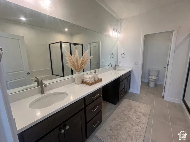 Dual sink vanity with white countertop and dark wood-finish cabinetry, featuring a large wall-mounted mirror