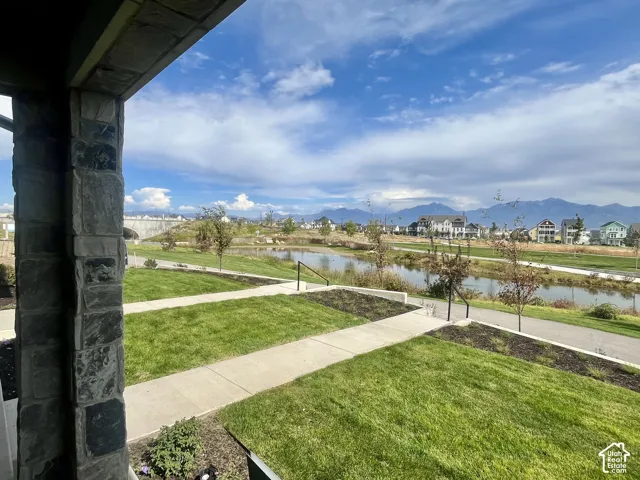 Stone column exterior with a manicured lawn, concrete walkways, and a water feature