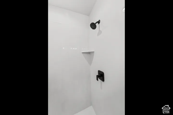 White shower stall with matte black shower fixtures and an integrated corner shelf
