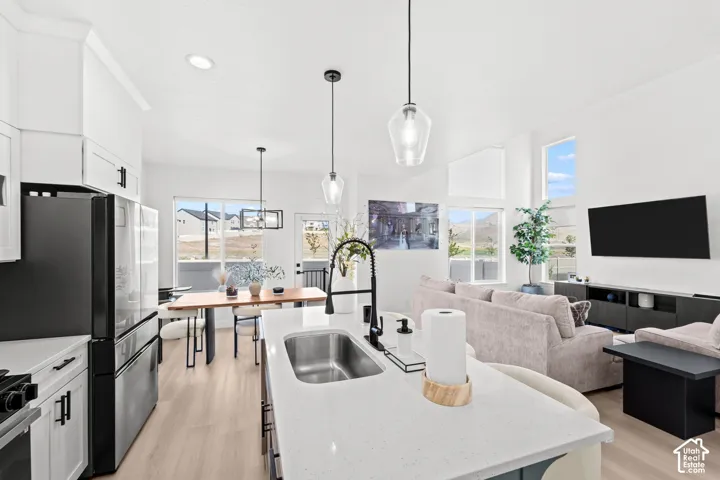 Open-concept living space with light wood-finish flooring, white walls, and recessed lighting