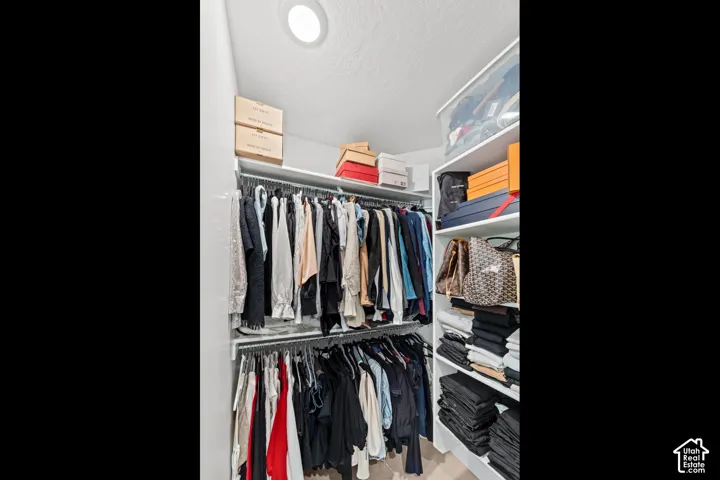 Recessed ceiling lighting illuminates a custom closet system featuring multiple shelves and hanging rods