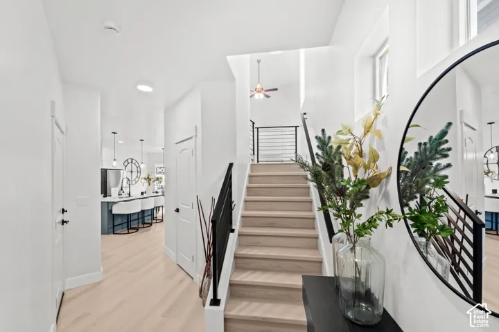 Light wood-finish flooring throughout, stairway with black metal railing, and white walls