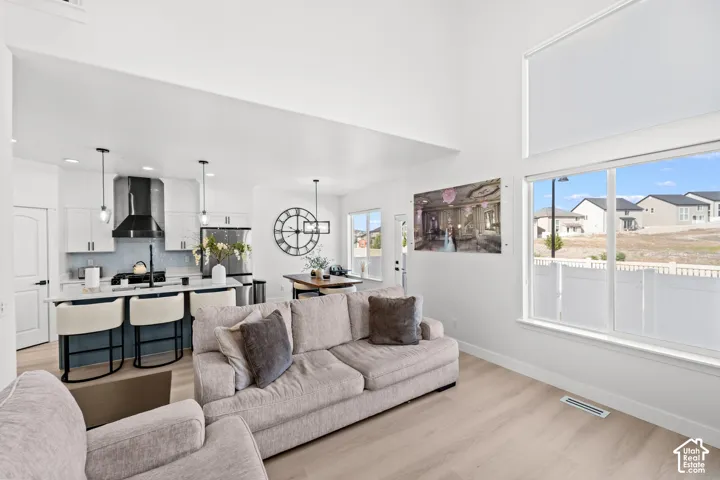 Open-concept living area featuring high ceilings, light wood-finish flooring, and expansive windows