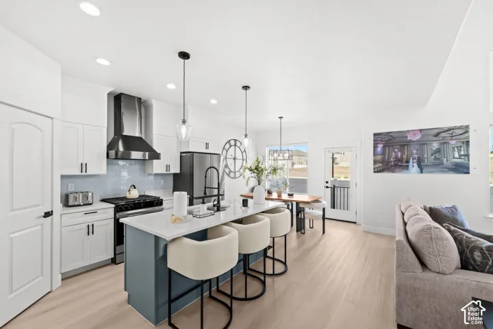 Gourmet kitchen with white cabinetry, stainless steel appliances, a tile backsplash, and a center island with seating