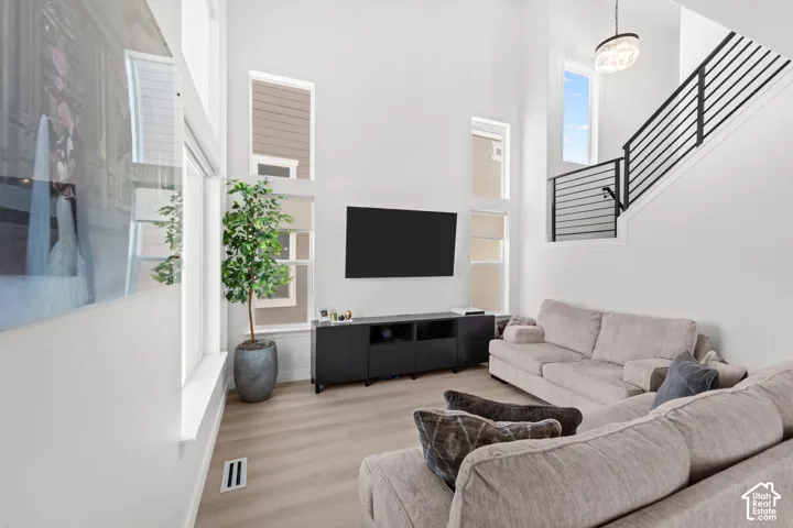 Vaulted ceilings, wood-finish flooring, multiple windows, and modern staircase with black horizontal balusters
