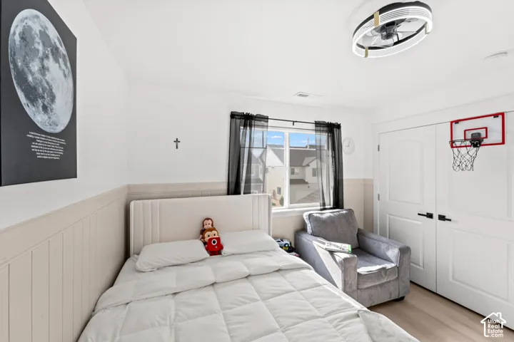 White walls with a light-toned wainscoting, light wood-finish flooring, and a contemporary ceiling fan